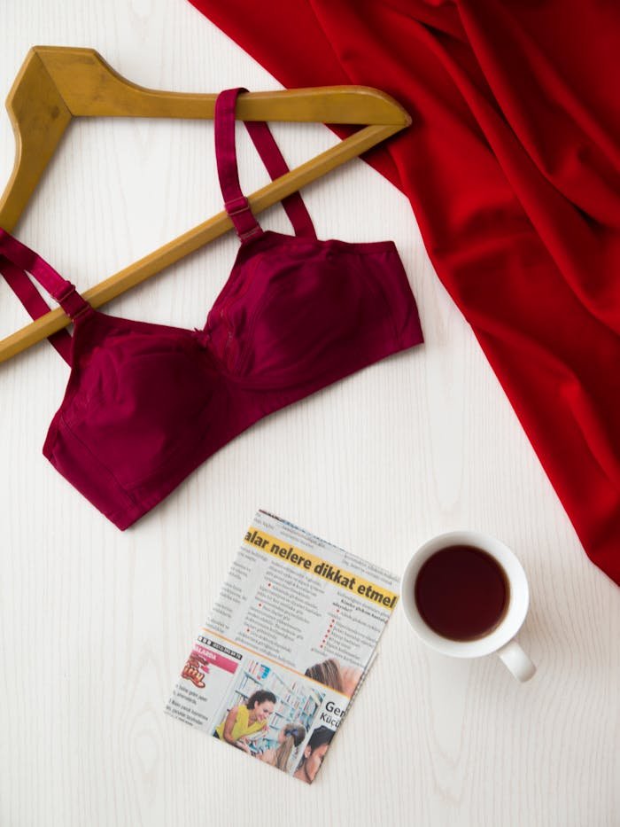 The Art of Drawing Readers In: Your attractive post title goes here Red bra on hanger, cup of tea, newspaper, and red fabric on a white table for a modern and stylish look.